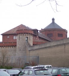 JVA Bruchsal - Was für ein bombastischer Klotz. Ein vierflügeliger Backsteinbau, an ein Panoptikum erinnernd,umgeben von einer begehbaren Sandsteinmauer und acht Wehrtürmen mit ziegelroten Zinnen. Im Mauergang patrouillieren Vollzugsbeamte mit Maschinenpistolen. Das gesamte Gelände ist nochmals von einem Metallzaun mit NATO-Stacheldraht bzw. einer grauen, stockfleckigen Betonmauer eingegrenzt. Das festungsähnliche Bauwerk steht zwischen Schloss und Krankenhaus in der Bruchsaler Innenstadt. Der Anblick vermittelt schon von außen: Hier wäre es schöner ohne das Gefängnis. Foto: Niels Seibert